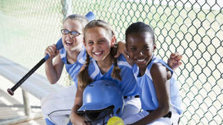 Multi culturele meisjes van baseballteam zitten in dug-out.